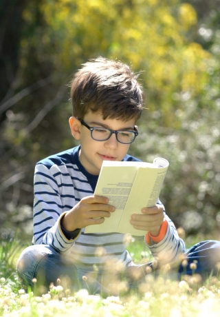 Happy child reading a book in forest